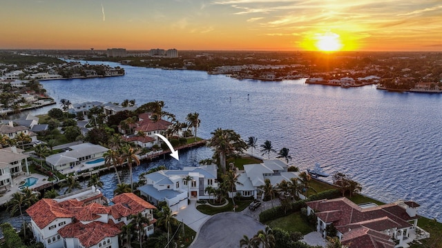 aerial view at dusk featuring a water view