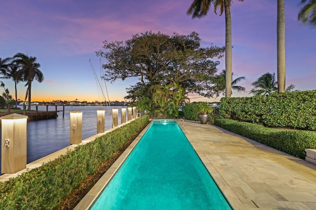 pool at dusk featuring a water view