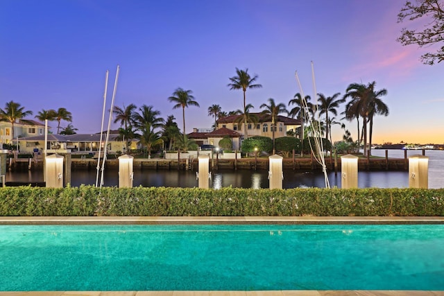 pool at dusk featuring a water view