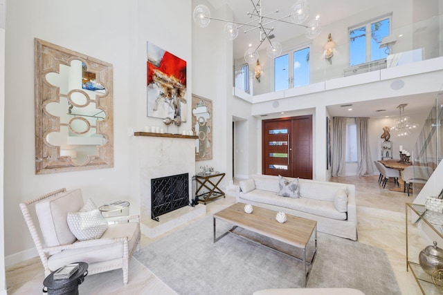 living room with a high ceiling, a high end fireplace, and an inviting chandelier