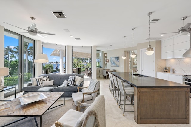 living room featuring ceiling fan, sink, and a wall of windows