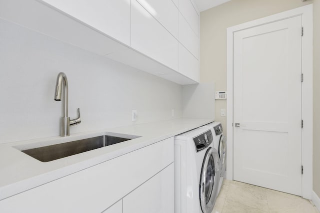 laundry area with cabinets, washing machine and dryer, and sink