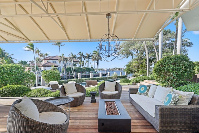 wooden terrace featuring a water view and an outdoor living space with a fire pit