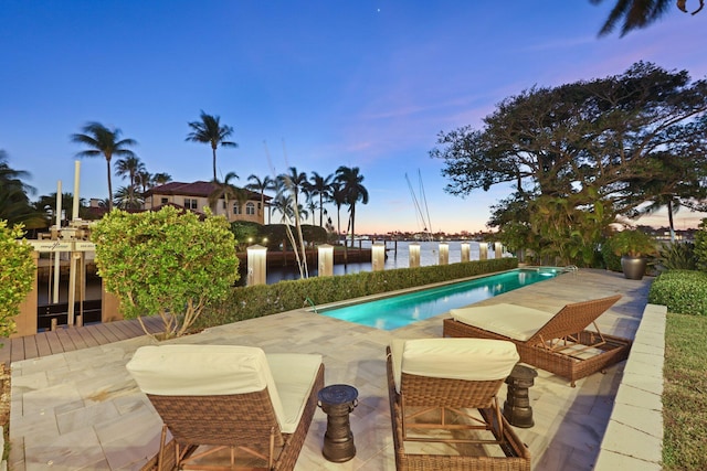 pool at dusk with a patio and a water view