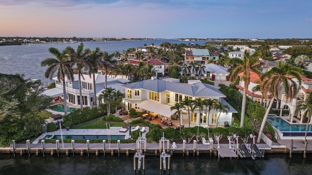 aerial view at dusk featuring a water view