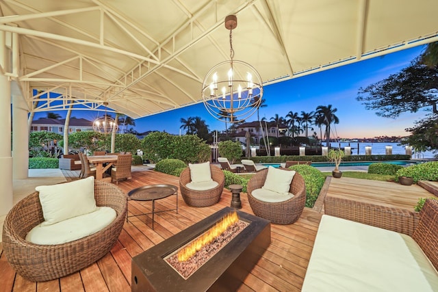 deck at dusk with a water view and an outdoor living space with a fire pit