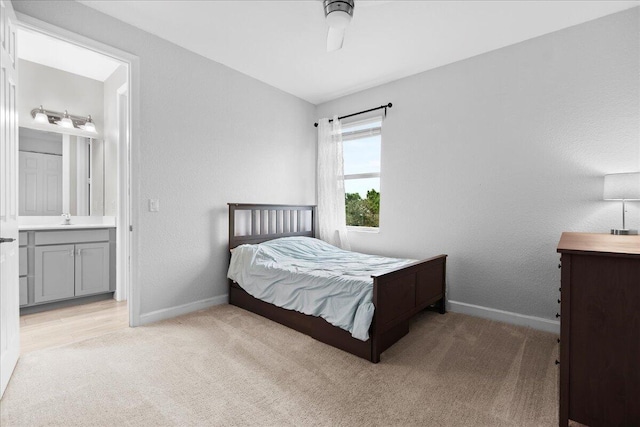 bedroom with sink, ensuite bath, light colored carpet, and ceiling fan