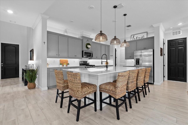 kitchen featuring appliances with stainless steel finishes, sink, a breakfast bar area, and a large island with sink