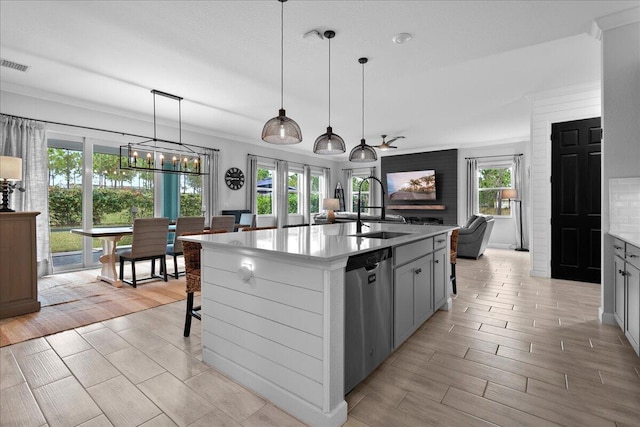 kitchen with sink, crown molding, dishwasher, an island with sink, and pendant lighting