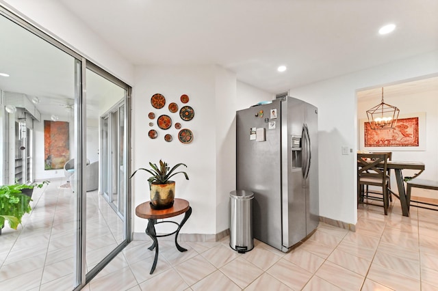 kitchen featuring recessed lighting, stainless steel refrigerator with ice dispenser, a notable chandelier, and baseboards