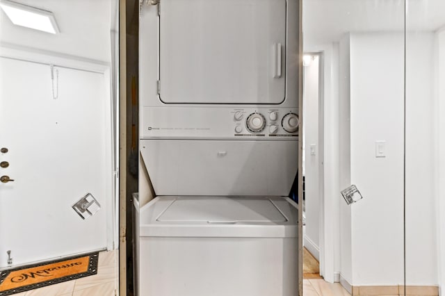 laundry room featuring stacked washer and dryer and light tile patterned floors