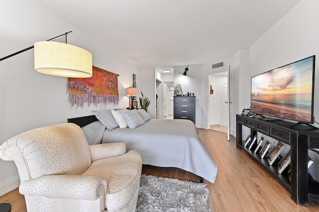 bedroom featuring light wood-style floors, visible vents, and baseboards