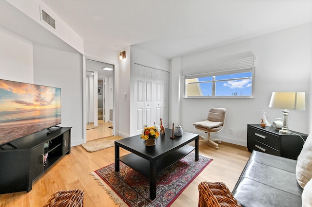 living area featuring light wood-style flooring, visible vents, and baseboards