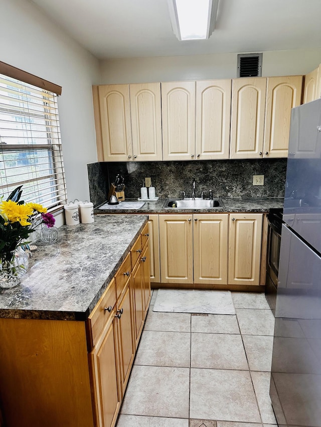 kitchen featuring sink, backsplash, stainless steel fridge, range with electric stovetop, and light tile patterned floors