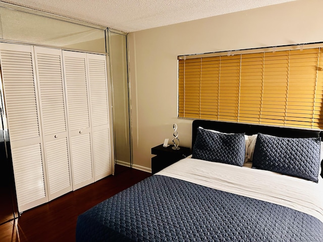 bedroom featuring a textured ceiling, a closet, and dark hardwood / wood-style flooring