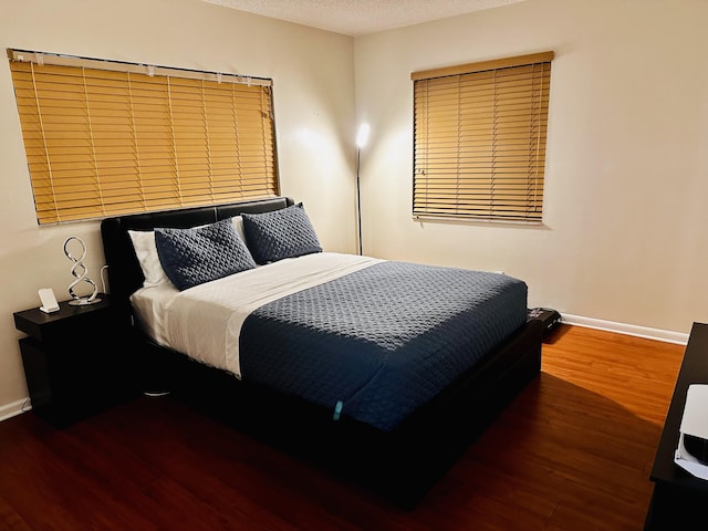 bedroom with a textured ceiling and dark hardwood / wood-style flooring