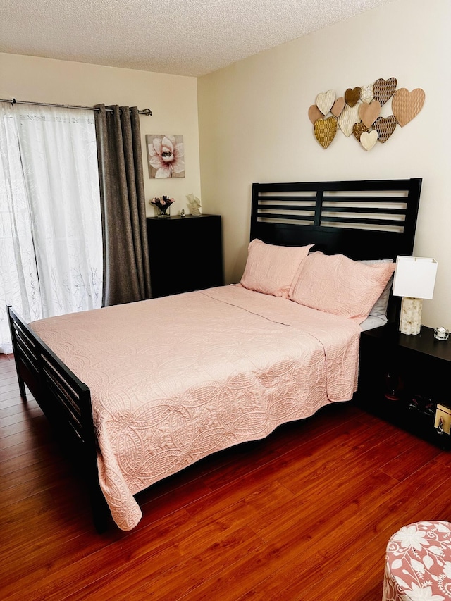 bedroom featuring a textured ceiling and dark hardwood / wood-style flooring