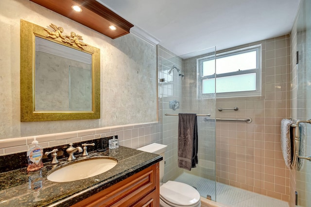 bathroom featuring tile walls, ornamental molding, vanity, toilet, and a shower with door