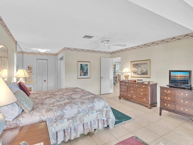 tiled bedroom with ceiling fan, a textured ceiling, and a closet