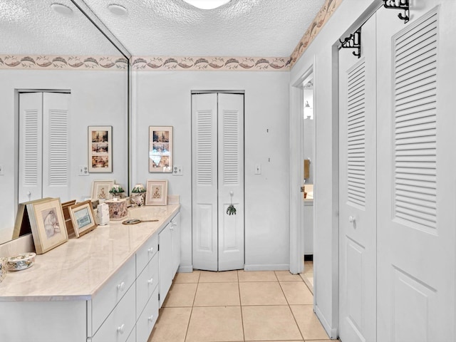 bathroom with a textured ceiling, tile patterned floors, and vanity