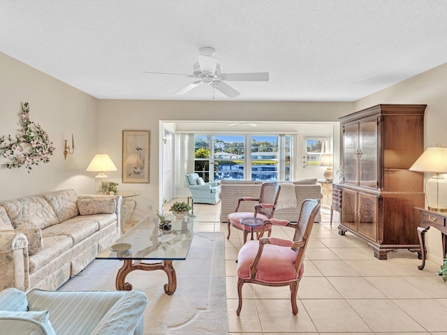 living room with ceiling fan, a textured ceiling, and light tile patterned flooring