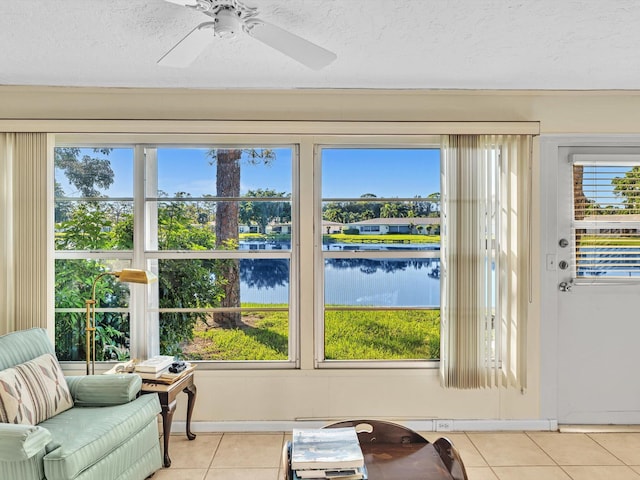 sunroom / solarium featuring ceiling fan, a water view, and a healthy amount of sunlight