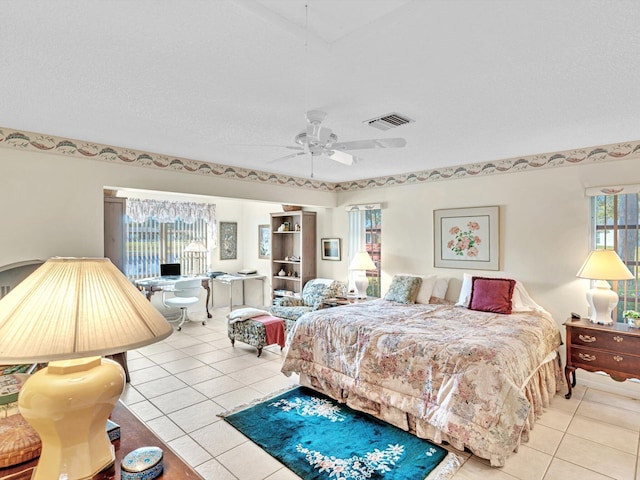 bedroom with ceiling fan, light tile patterned floors, and a textured ceiling