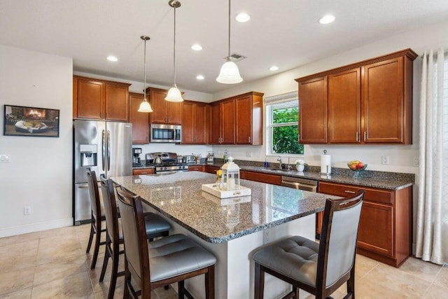 kitchen with appliances with stainless steel finishes, a center island, decorative light fixtures, a kitchen bar, and sink