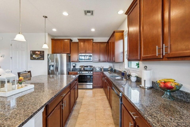 kitchen with pendant lighting, appliances with stainless steel finishes, sink, light tile patterned floors, and dark stone countertops