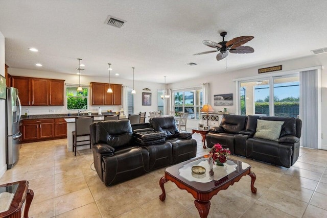 tiled living room featuring ceiling fan and a textured ceiling