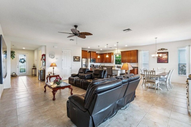 tiled living room with ceiling fan with notable chandelier