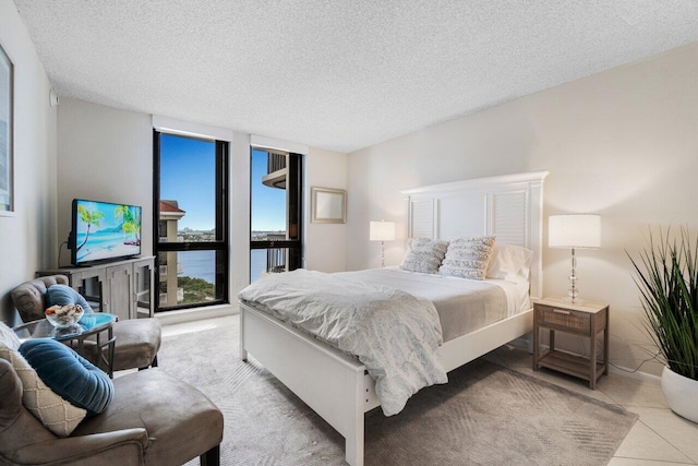 bedroom featuring light tile patterned flooring, access to exterior, a textured ceiling, and floor to ceiling windows