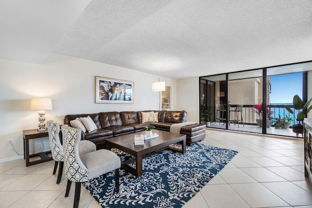 living room featuring a textured ceiling, light tile patterned floors, and expansive windows