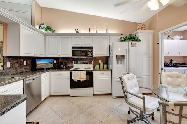 kitchen with lofted ceiling, white appliances, white cabinetry, and washing machine and clothes dryer