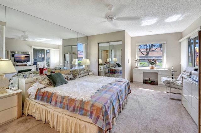 bedroom with a textured ceiling, light colored carpet, and ceiling fan