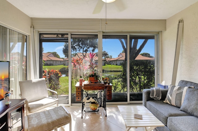 sunroom with ceiling fan and a water view