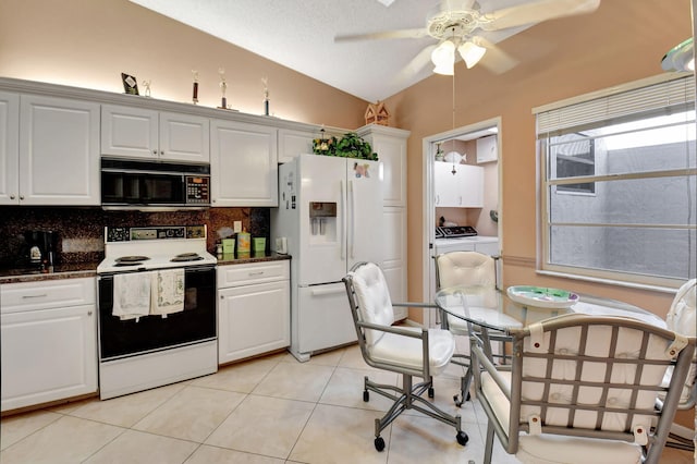 kitchen with lofted ceiling, white appliances, washer and clothes dryer, and white cabinets