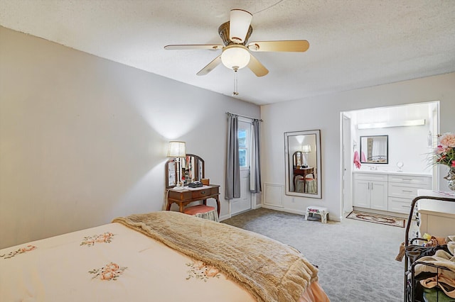 carpeted bedroom with ceiling fan, connected bathroom, and a textured ceiling