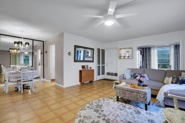 living room featuring ceiling fan with notable chandelier and a textured ceiling