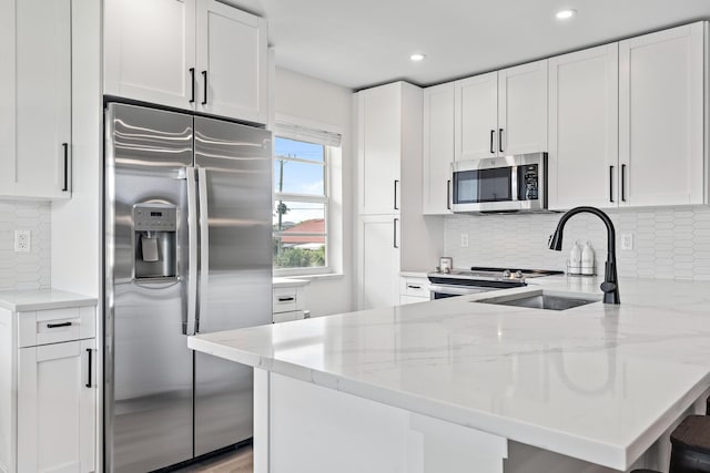 kitchen featuring white cabinetry, stainless steel appliances, sink, and light stone counters