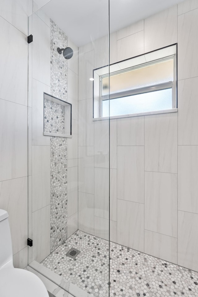 bathroom with tiled shower and toilet