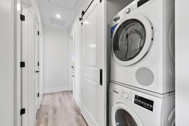 clothes washing area with stacked washer / drying machine and light hardwood / wood-style flooring