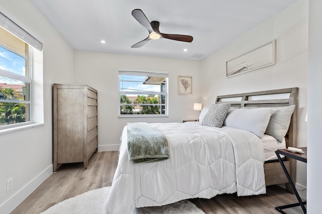 bedroom featuring ceiling fan, light hardwood / wood-style floors, and multiple windows