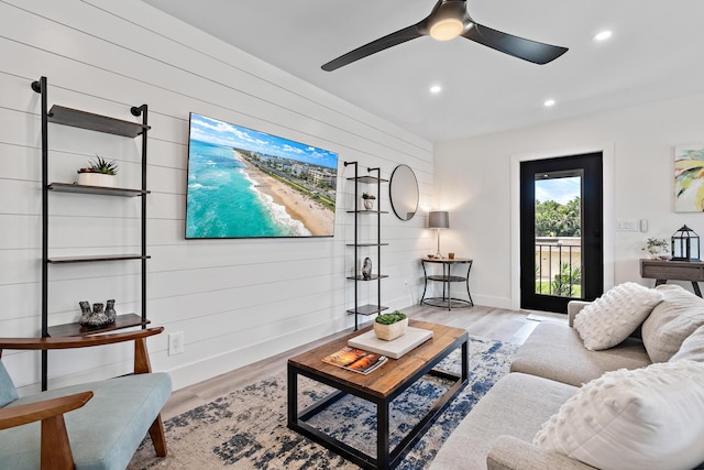 living room featuring wood walls, ceiling fan, and light hardwood / wood-style flooring