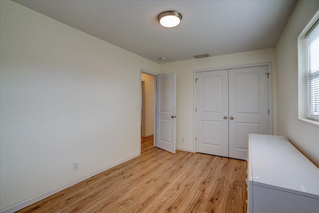 unfurnished bedroom with a closet and light wood-type flooring