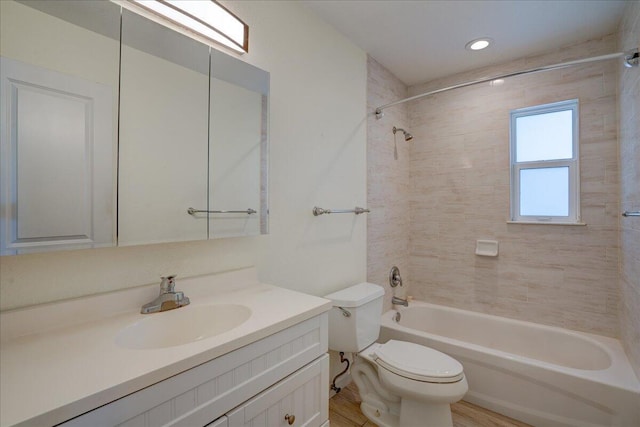 full bathroom featuring tiled shower / bath, vanity, and toilet