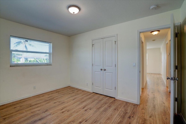 unfurnished bedroom featuring light hardwood / wood-style flooring and a closet