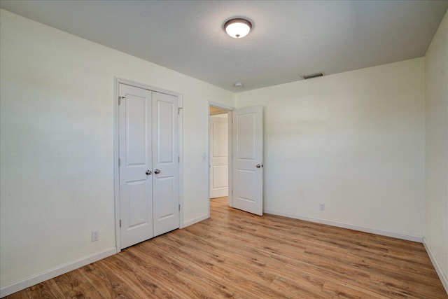 unfurnished bedroom with light hardwood / wood-style flooring and a closet