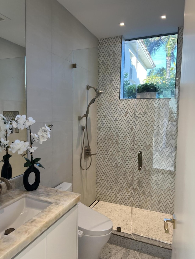 full bath featuring a stall shower, tile walls, vanity, and toilet