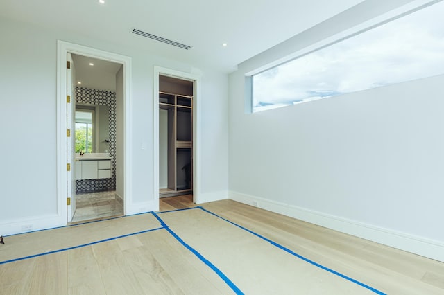 unfurnished bedroom with recessed lighting, wood finished floors, visible vents, baseboards, and a closet